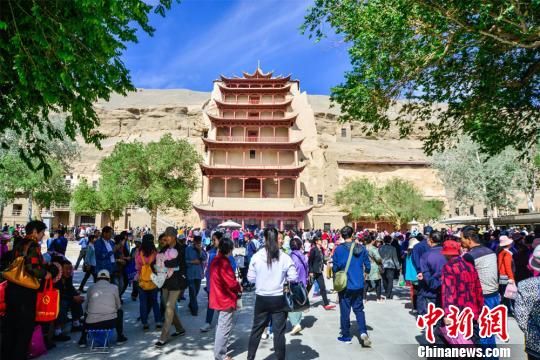 2018年5月22日，中国农历四月初八，甘肃敦煌数万民众传承历史习俗，早早前往莫高窟烧香礼佛、祈福，莫高窟九层楼前人潮涌动。(资料图) 王斌银 摄
