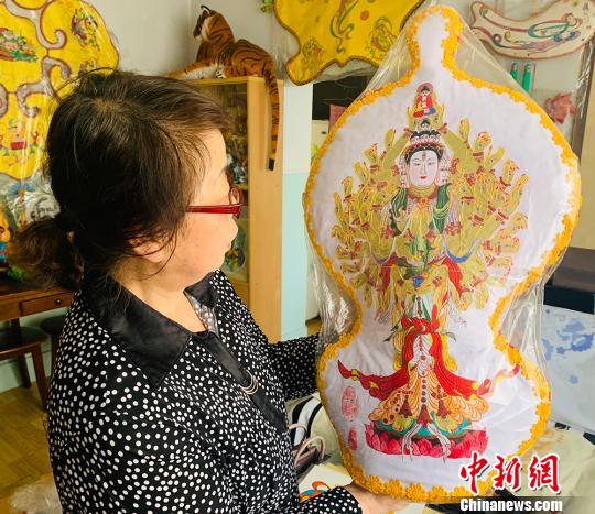 图为丁永莲向记者介绍“千手观音”，该作品耗时半年。　高康迪 摄