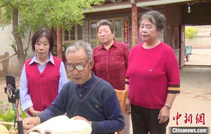 王跃庆低头念唱河西宝卷。 王菲 摄 王跃庆低头念唱河西宝卷。 王菲 摄