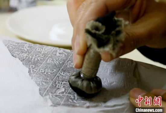 麻晓雷用拓包蘸上墨汁一点点进行拓印,不同的凹凸面所需力道也不同。 高展 摄 麻晓雷用拓包蘸上墨汁一点点进行拓印,不同的凹凸面所需力道也不同。 高展 摄