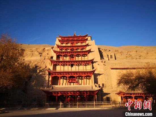 图为11月7日,沐浴在晨光中的敦煌莫高窟标志性建筑“九层楼”。 冯志军 摄 图为11月7日,沐浴在晨光中的敦煌莫高窟标志性建筑“九层楼”。 冯志军 摄