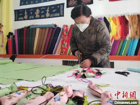 图为甘肃庆阳香包传承人刘兰芳裁剪布料，用于制作防疫“平安香包”。　甘肃省非物质文化遗产保护中心提供