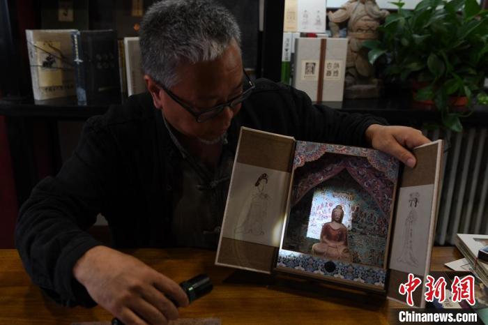 图为读者出版集团读者晋林工作室独立出品人徐晋林,展示互动性强的敦煌题材手工书。(资料图) 杨艳敏 摄 图为读者出版集团读者晋林工作室独立出品人徐晋林,展示互动性强的敦煌题材手工书。(资料图) 杨艳敏 摄