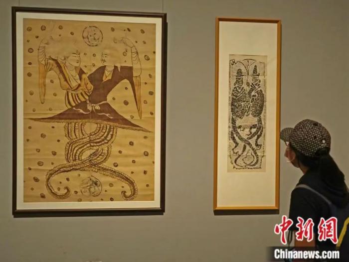 2021年5月，在北京举行的“图画众生——河西画像砖上的古人生活”展览上，《唐人伏羲女娲像立幅》(左)、《伏羲女娲汉画像石拓片》(右)吸引参观者。中新社发 石艺媛 摄