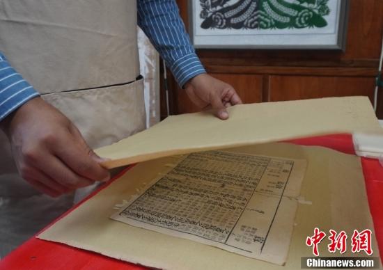 图为该校古籍修复师用吸水纸吸收古籍上的水分。 中新社记者 九美旦增 摄 图为该校古籍修复师用吸水纸吸收古籍上的水分。 中新社记者 九美旦增 摄