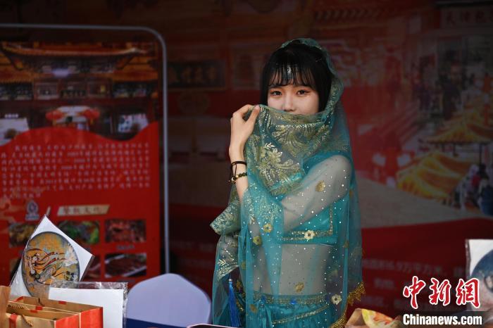 图为活动现场工作人员展示推荐西域服饰等敦煌文旅产品。　李亚龙 摄