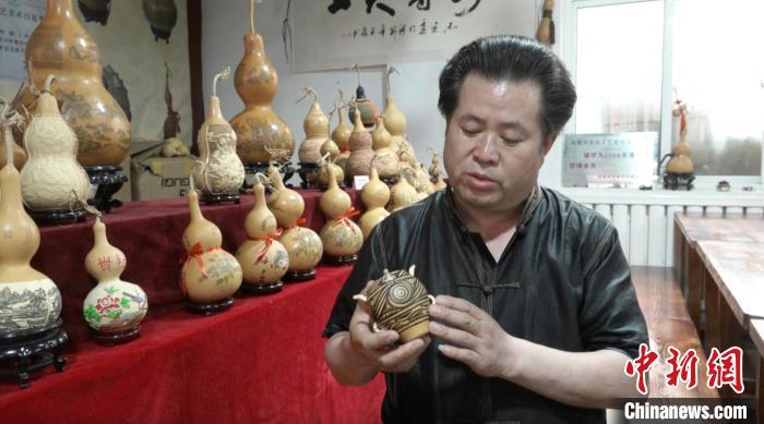 图为临夏雕刻葫芦州级传承人白正兵展示彩陶纹饰葫芦作品。田鹏鹤 摄 图为临夏雕刻葫芦州级传承人白正兵展示彩陶纹饰葫芦作品。田鹏鹤 摄