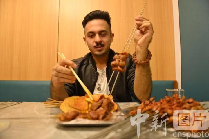10月23日,甘肃兰州,兰州理工大学留学生潘迪在晚餐时间品尝兰州烤肉。 10月23日,甘肃兰州,兰州理工大学留学生潘迪在晚餐时间品尝兰州烤肉。