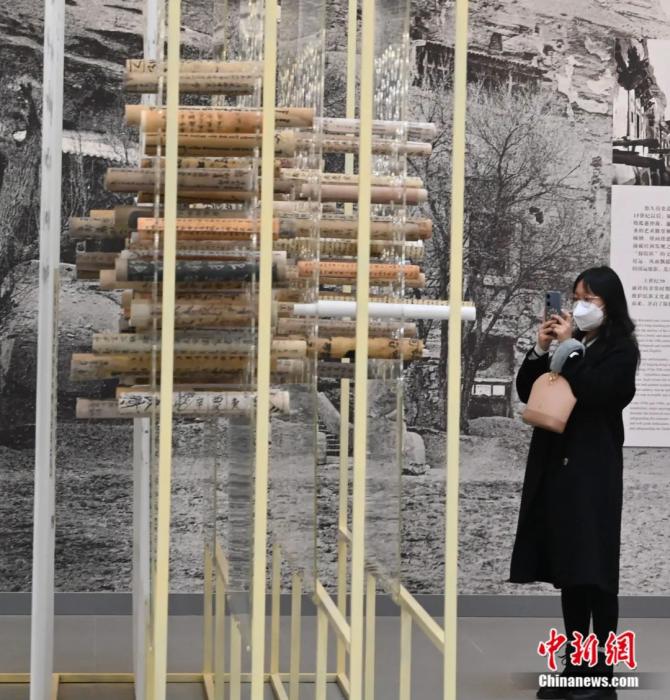参观者在敦煌艺术馆用手机拍摄敦煌文献复制品卷轴墙。九美旦增 摄