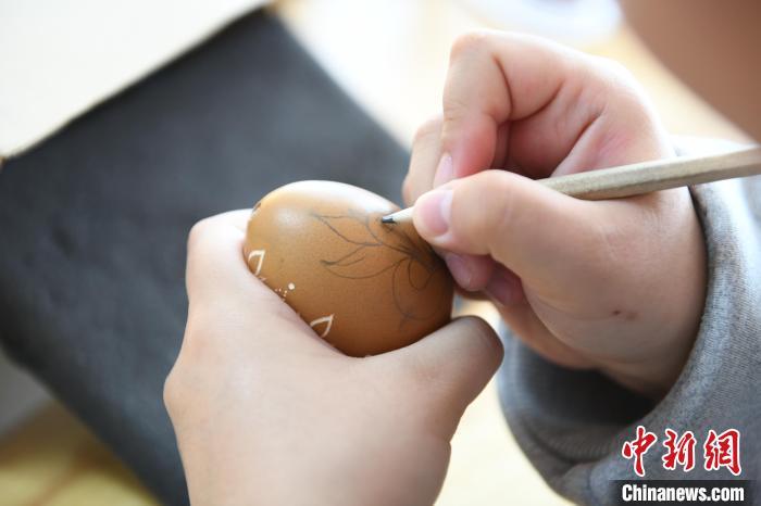 图为学生在蛋壳上绘制图案。戴文昌 摄

