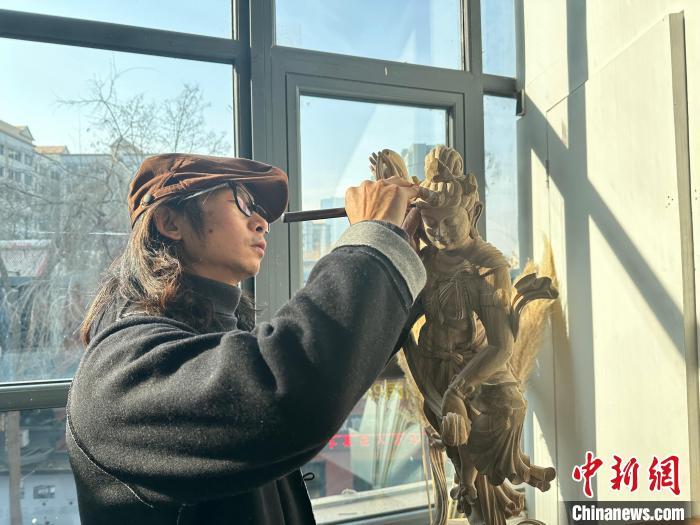 图为甘肃省敦煌木雕技能大师进行敦煌木雕的创作。王牧雨 摄 图为甘肃省敦煌木雕技能大师进行敦煌木雕的创作。王牧雨 摄