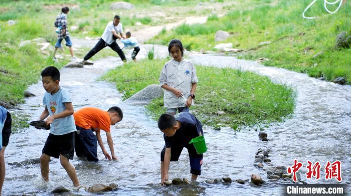7月2日，紧邻国家4A级旅游景区“陇右名山”兴隆山的村落——兰州市榆中县新营镇八门寺村，蜿蜒向前的溪水涓涓流淌，绿树成荫、草木茂盛，一顶帐篷，一张餐桌，三五好友……随处可见来这里露营纳凉的游人，徜徉在这片“绿野仙踪”里，悠闲自在、心旷神怡。图为小孩子在溪水里嬉戏。张文 摄

　　