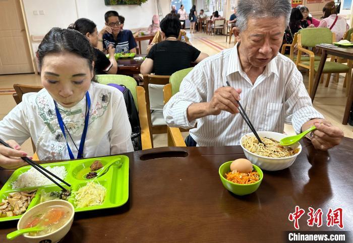 图为王金城(右)和陈习珍(左)在兰州一家社区养老中心用午餐。丁思 摄
