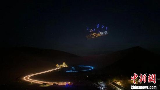 6月15日，敦煌鸣沙山万人星空演唱会启幕。图为灯光点亮月牙泉，无人机在夜空形成沙漠驼铃画面。九美旦增 摄