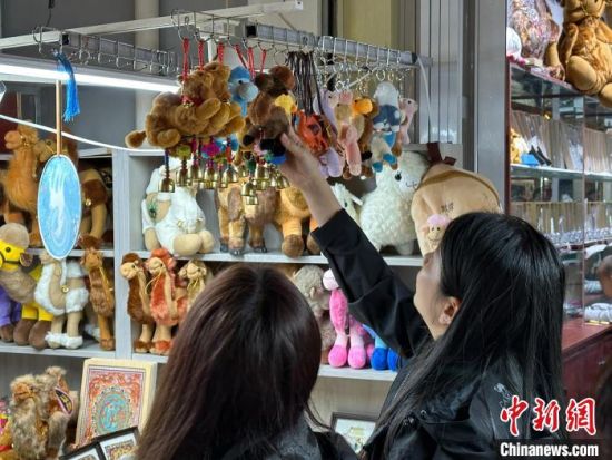 图为游客选购骆驼挂件。王牧雨 摄