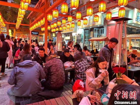 图为游客在敦煌夜市品尝特色美食。王牧雨 摄
